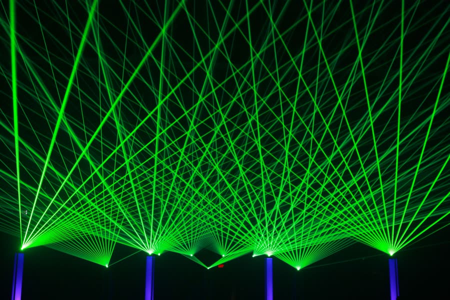 Eleven laser projectors casting fans of green beams over a large venue, a Dam Lasers beam show