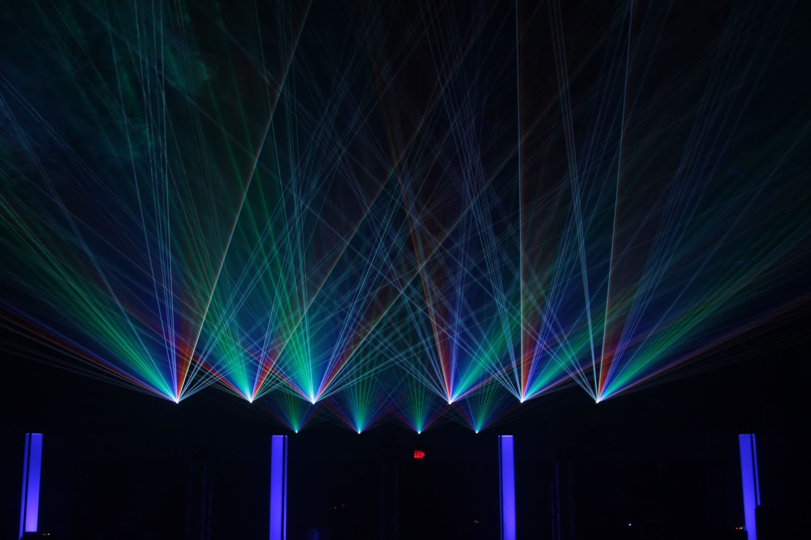 Cyan, blue and violet laser beams projected across a dark venue at a Dam Lasers show, Amsterdam