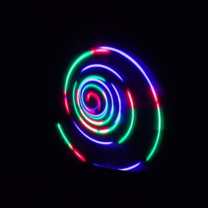 A multi-coloured spiral ellipse drawn by a laser graphics projector