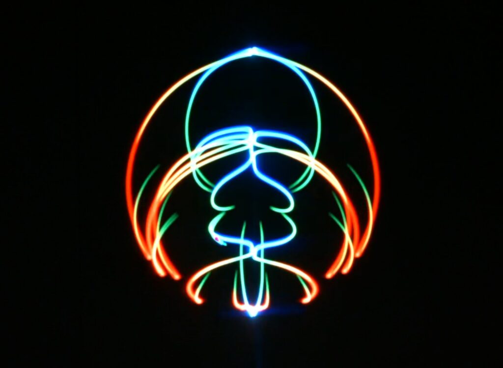 Abstract laser graphic drawn as one continuous line in orange, green and cyan against darkness